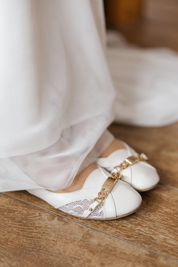 Weiße Hochzeitsschuhe mit Spitzen und Kettendetails.