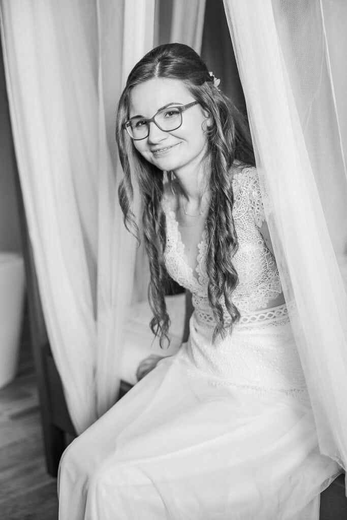Frau im Brautkleid zwischen Gardinen