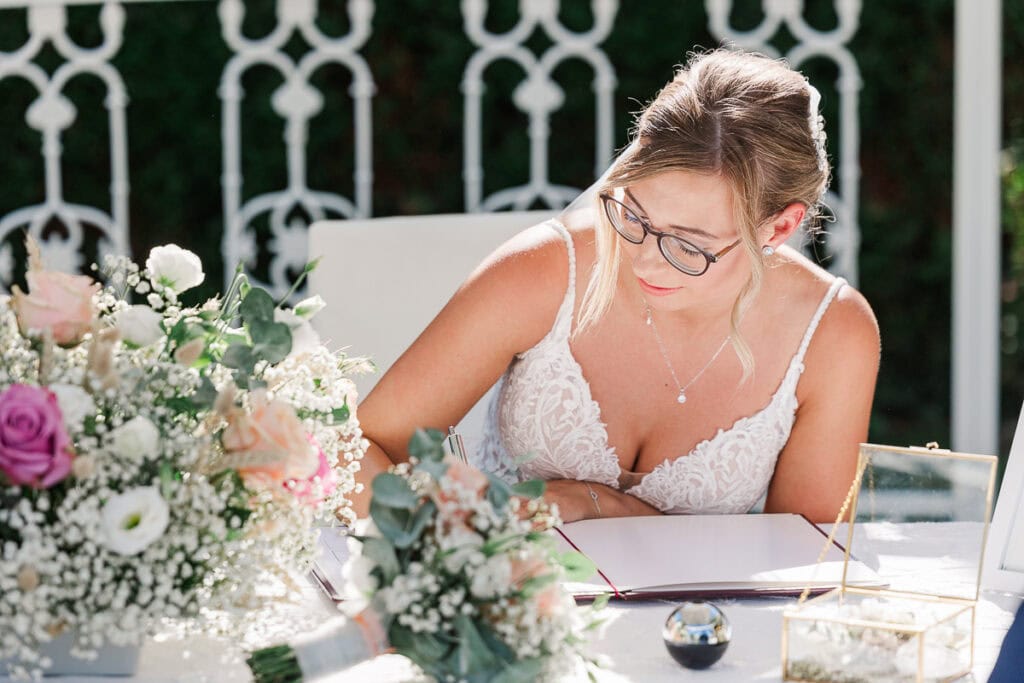 Braut unterschreibt am Tisch mit Blumen